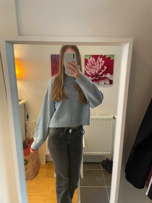 Ljusblå cropped stickad tröja - Säljer en ljusblå cropped stickad tröja med rund hals och långa, något vida ärmar. Tröjan har en enkel och stilren design utan synligt märke och är gjord i ett mjukt, tunt stickat material. 