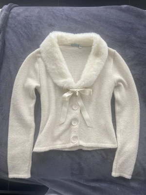 Vintage fur kofta vit  - Supersöt vit kofta från Suzanna med fluffig fuskpäls runt kragen och stora knappar. Storlek S 