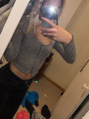 Blå ribbad croppad topp - Blå croppad topp med lång ärm och ribbad struktur. Toppen har knappar framtill och en v-ringad halsringning. Perfekt för en trendig och avslappnad look.