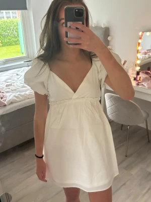 Vit klänning med puffärmar - Säljer en vit klänning med puffiga korta ärmar och djup v-ringning. Klänningen har en markerad midja. Passar mig som är 170 och klänningen är endast använd en gång! 