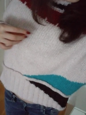 Stickad tröja med färgblock - Mysig stickad tröja med hög krage i ljusrosa, rött, svart och turkost. Tröjan har en lös men croppen passform och ribbstickade muddar. Perfekt för kalla dagar och ger en cool retrovibe till din outfit.