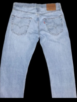 Ljusblå raka jeans från Levi's - W28 L32. Säljer ett par feta ljusblå jeans från Levi's med raka ben och femficksmodell. Jeansen har den ikoniska läderlappen bak i midjan och röd Levi's-tagg på bakfickan. Tillverkade i slitstark denim, perfekta för en avslappnad look.