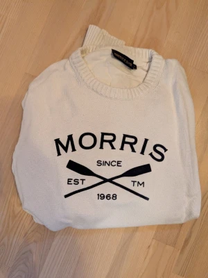 Vit stickad tröja från Morris - Vit stickad tröja från Morris med svart tryck framtill där det står 'Morris Since 1968' och två korsade åror. Storlek L, väldigt fint skick.