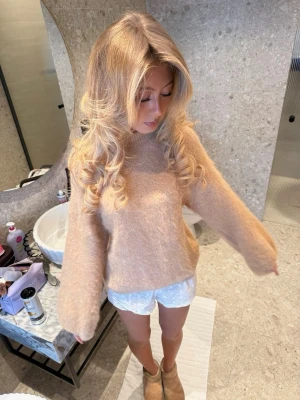 Beige fluffig stickad tröja H&M - Mysig beige stickad mohair tröja från H&M Edition i fluffigt material. Tröjan har rund halsringning, långa ärmar och en avslappnad passform. Perfekt för lager på lager och ger en trendig look till hösten och vintern. 