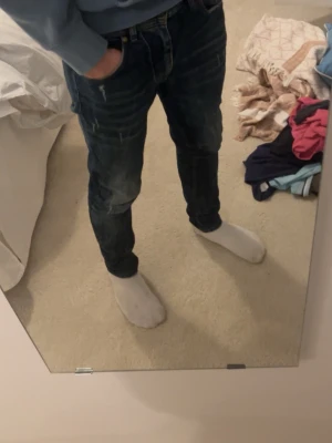 Mörkblå slim fit jeans - Snygga mörkblå slim fit jeans med lätt slitna detaljer och klassisk femficksdesign. Jeansen har en modern passform och är perfekta för en trendig vardagslook. Materialet är denim med stretch för extra komfort.