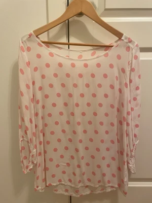 Vit blus med rosa prickar - Söt och luftig vit blus med rosa prickar och rund halsringning. Blusen har trekvartsärm och är tillverkad i ett tunt, transparent material som ger en avslappnad och trendig look. Perfekt att matcha med jeans eller kjol för en lekfull stil.klippt bort etiketten, så minns inte om det var mq eller flash. Passar S och m. Mjuk och skön