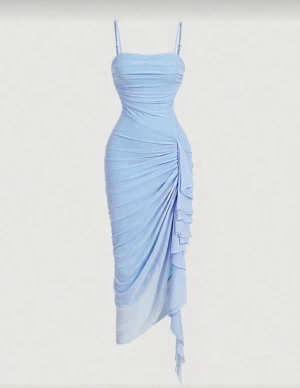 Ljusblå långklänning med volang - Säljer en ljusblå långklänning med smala axelband och figurnära passform. Klänningen har snygga draperingar och en volangdetalj längs sidan som ger extra stil. Materialet är mjukt och stretchigt, perfekt för sommarkvällar. Passar dig som gillar en elegant och modern look.