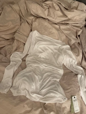 Vit långärmad topp från Intimissimi - Säljer en stilren vit långärmad topp från Intimissimi. Toppen är gjord i mjuk bomull och har en klassisk passform med rund halsringning. Perfekt att matcha med jeans eller kjol för en clean look.💗
