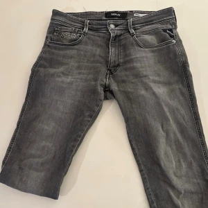 Grå jeans från Replay - Snygga grå jeans från Replay med klassisk femficksdesign och raka ben. Jeansen har en diskret tvättad look och silverfärgade detaljer vid knappar och nitar. Perfekta för en avslappnad och trendig stil.