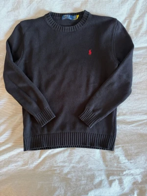 Svart stickad tröja från Polo Ralph Lauren - Svart stickad tröja från Ralph Lauren med klassisk rund halsringning. Tröjan är i mycket gott skick med minimala tecken på användning. Hör gärna av dig vid frågor eller för fler bilder.