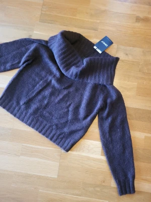 Stickad off shouldertröja  - Säljer en mörkbrun stickad off shoulder tröja från Gina tricot med bred, ribbad krage och långa ärmar. Tröjan har en croppad passform och är gjord i ett mjukt, fluffigt material som känns riktigt cozy. Perfekt för kyliga dagar och enkel att styla till jeans eller kjol. Helt oanvänd med lappen kvar