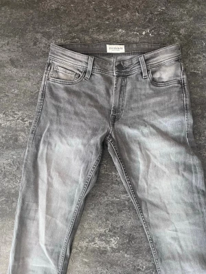 Grå jeans från Stock & Hank slim fit - Snygga grå jeans från Stock & Hank med klassisk femficksmodell och normal midja. Jeansen har en lätt tvättad look och raka ben. Perfekta för en avslappnad och trendig stil.