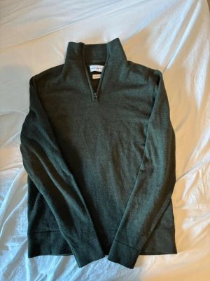 Mörkgrön halvzip tröja - Mörkgrön stickad halfzip från these glory days. Tröjan är gjord av merinoull vilket gör den väldigt mjuk. 