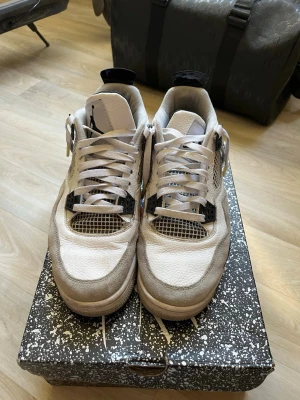 Air Jordan 4 vi kan förhandla! - Snygga Air Jordan 4 Retro Off-White Sail sneakers med vit och beige ovandel i läder och mesh, svarta detaljer och klassisk siluett. Ikonisk Jumpman-logga på plösen och coola plastdetaljer vid snörningen. Perfekta för dig som gillar streetwear och vill sticka ut.
