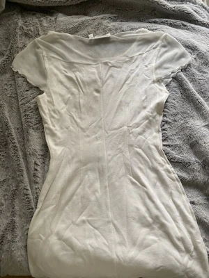 Vit kortklänning från Kappahl - Snygg vit kortklänning från Number One by Kappahl. Klänningen har korta ärmar och en enkel, figurnära passform med rundad halsringning. Materialet känns mjukt och lätt, perfekt för varmare dagar. 