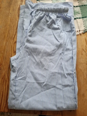 Randiga pyjamasbyxor i bomull - Snygga pyjamasbyxor med smala blå och vita ränder. Byxorna har resår i midjan och är gjorda i ett mjukt bomullstyg, perfekta för att chilla hemma. Klassisk och avslappnad passform.