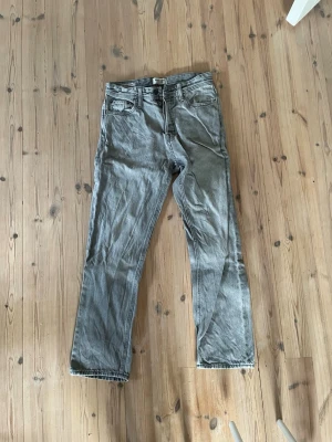 Jack and jones jeans relaxed - Säljer ett par grå jeans med rak passform och klassisk femficksdesign. Jeansen har bälteshällor och knappgylf. Perfekta för en avslappnad och stilren look.