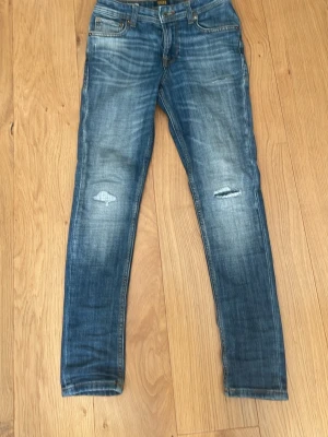 Blå skinny jeans från Jack & Jones - Snygga blå skinny jeans från Jack & Jones med slitningar på knäna och klassisk femficksdesign. Jeansen har dragkedjegylf och tydliga tvättade detaljer för en cool look. Perfekta för dig som gillar en avslappnad och trendig stil. I vuxen storlek är det ungefär W25 L28. Jag på bilden är 162.