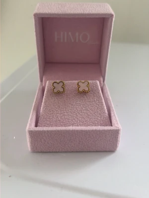 Guldrosa örhängen från HIMO - Snygga fyrkantiga örhängen från HIMO i guldton med pärldetaljer runt kanterna. De har en stilren och modern design som passar perfekt till dig som gillar unika accessoarer. Kommer i en söt rosa ask och är helt oanvända då dem inte riktigt är i min stil. 19k guldplaterat och vattentåliga. Pris kan diskuteras!🌺