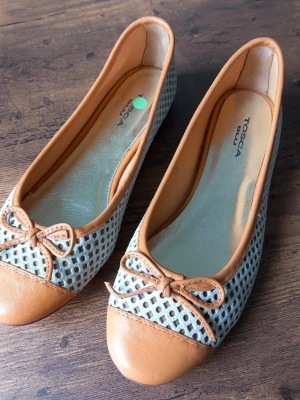 Ballerinaskor Tosca Blu med rosett storlek 38 - Snygga ballerinaskor från Tosca Blu i beige och ljusblått. Skorna har ett nätmönstrat tyg, detaljer i läder och en söt rosett framtill. Rund tå och låg klack gör dem både stilrena och bekväma. Perfe5kta för dig som gillar en chic och trendig look.