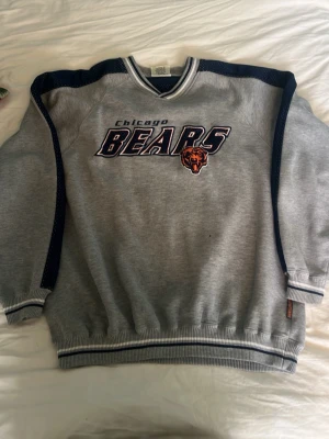 Chicago Bears Sweatshirt  - Vintage inspirerad sweatshirt med broderat ”Chicago Bears” tryck framtill och mörkblå detaljer längs ärmarna. Skön oversized/passform, perfekt för streetwear eller en nice vintage stil. Fortfarande i riktigt bra skick. Skriv gärna för mer bilder