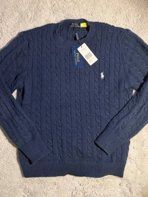 Polo Ralph Lauren Kabelstickad Tröja - Helt ny Polo Ralph Lauren herrtröja med kabelstickning i klassisk marinblå färg, tillverkad av mjuk bomull som passar perfekt till perfekt för kyliga sommarnätter  || ⭐️ Skick: 10/10 som ny  ||  📐  Storlek: M ||   📦 Snabb och noggrann frakt .