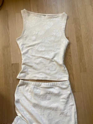 Lång kräm/vit gina studentklänning 2 piece blommor - En suuperfin studentklänning från gina. är boatneck. Köpt förra året och bar använd en gång (studenten :D), köpt för ca 900kr i butik. Lapp avklippt men överdel är S och kjol är M. För mig som är 160 är kjolen lite lång, fick vika upp den en liten bit, men om du är längre passar den nog dig bra! Baksidan av tröjan samt nedre delen av kjolen är gjort av ett tunnare material. Nästintill perfekt skick, bara använd en gång. Ända tydliga defekt jag kunde se är fotad i bild 5. Skriv vid frågor!