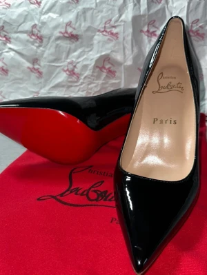 Christian Louboutin klackskor - Christian Louboutin klackskor i svart lack, storlek 37.Levereras med röd påse med Christian Louboutin tryck enligt bild, lådan finns 