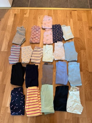 Flera olika barnkläder från byxor,t-shirt, tröjor,pyjamas och babybodys från storlek 80-104 - Säljer ett stort set med olika barnkläder i olika färger och mönster. Färgerna går i pastelltoner som lila, grön, beige och rosa, samt några med blommigt mönster. OM NI VILL BARA KÖPA ETT PAR SÅ ÄR DET BARA ATT HÖRA AV SIG 