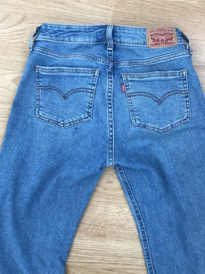 Levi’s jeans: Blå bootcut low-waisted:) - Säljer dessa fina blåa low wasied Levis jeans i stl Xs, sitter tight vid låren och går ut lite lätt vid smalbenen. Jeansen har fint läderpatch bak i linningen. Tillverkade i slitstark denim med lätt tvättad look. 