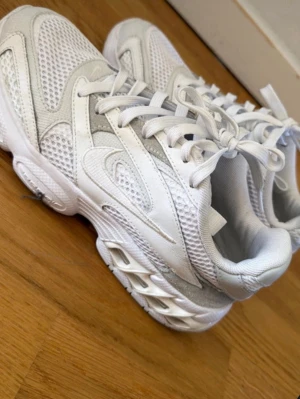 Vita mesh sneakers med chunky sula - Snygga vita sneakers med meshpaneler och detaljer i syntetläder. Skorna har en chunky sula och klassisk snörning. Perfekta för dig som gillar sportig och trendig stil. Luftiga och bekväma för vardagsbruk.