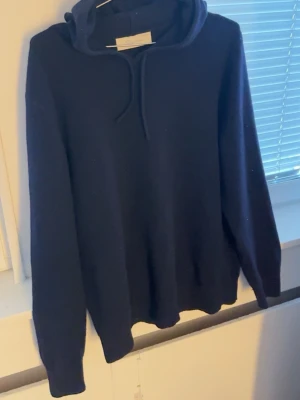 Mörkblå hoodie från Sayless - Riktigt snygg mörkblå hoodie från Sayless i cashmere. Klassisk modell med huva, samt långa ärmar. Perfekt för dig som gillar stilrena och bekväma plagg. 