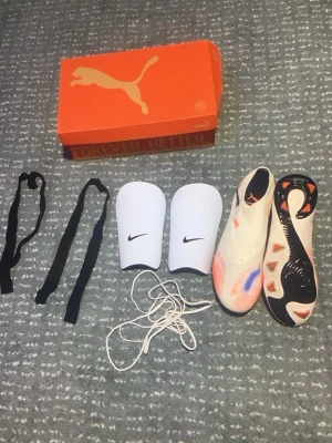 Vita Nike benskydd & Puma fotbollsskor - Fotbollsbundle perfekt för en match  inkluderar( fotbollskor från stadium storlek 41,5 1200kr) fotbollshandskar Nike ( från xxl  300kr ungefär) (benskydd från Nike vita får med band så man även kan spänna fast cirka 400)