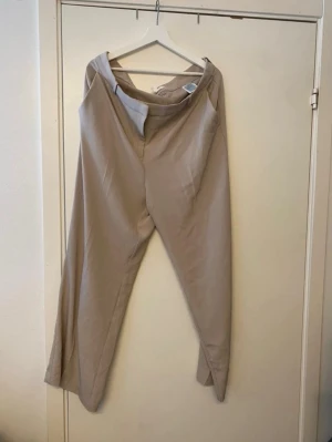 Beige kostymbyxa från H&M - Snygg beige kostymbyxa från H&M med rak passform och hög midja. Använt en gång men i väldigt bra skick. Storlek 50