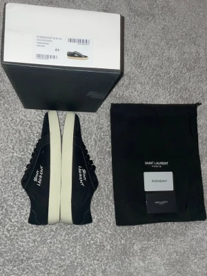 Svarta Saint Laurent sneakers - Snygga svarta sneakers från Saint Laurent. 'Saint Laurent' broderad på sidan. Materialet är en mix av mocka och läder för en exklusiv känsla. Innersulan: 28cm
