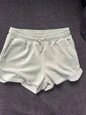 Ljusgröna mjuka shorts med snörning - Snygga ljusgröna shorts i mjukt frottématerial med elastisk midja och snörning framtill. Shortsen har två sidofickor och en avslappnad passform, perfekta för varma dagar.