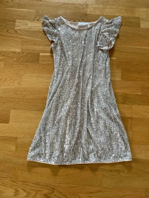 Festklänning från Kappahl - Säljer denna jättefina glittriga klänning från Kappahl. Den är i stl 146, men är lite liten för mig som är 170 och brukar ha xs-s, det beror på hur man vill att den ska sitta. Den är 67 cm uppifrån och ner. Den har även en klänning under så den är inte genomskinlig. Den säljs inte längre och är i bra skick tror jag har använt den en gång. Hör av er om frågor och kontakta mig innan köp!💗(Säljer även på Vinted ifall man skulle vilja köpa där)