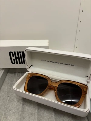 Chimi peach 008 - Snygga solglasögon från Chimi med transparent peach färgad båge och mörka glas. Modellen har en fyrkantig form som ger en trendig look. Kommer med originaletui och box. Solglasögonen är i ett bra skick, inte alls mycket tecken på slitage/använding. Fodralet och boxen har däremot tecken på slitage, men glasögonen är i ett fint skick!