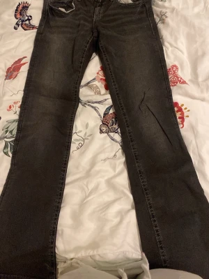 Svarta bootcut jeans från Gina Tricot - Säljer ett par svarta bootcut jeans från Gina Tricot med klassisk femficksmodell och guldfärgade knappar. Jeansen har en lätt utsvängd passform och är tillverkade i denim med lite stretch för extra komfort. Används inte längre pga blivit längre. Passar folk som är 164 långa