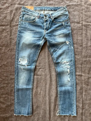 Slitna Dondup George jeans, storlek 29 - Blå Dondup jeans i eftertraktade modellen George med ett nypris på ca 2800 kr. Jeansen är slitna och tvättade. Storlek i jeansen är 32 men de upplevs som ungefär 29. Midjebredd: 40 cm Längd: 92 cm