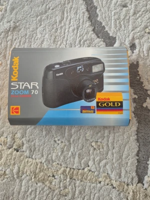 Kodak Star Zoom 70 kompaktkamera - Kodak Star Zoom 70 i ett fantastiskt skick. Kameran fungerar felfritt och är redo för användning. Det är en smidig och klassisk 35mm-kamera som är perfekt för både nybörjaren och den som vill ha en pålitlig analog kamera Specifikationer:  Modell: Kodak Star Zoom 70  Filmtyp: 35mm  Skick:Testad och fungerar felfritt.  Medföljer: Originalkartong och originalmanual samt batteri. 