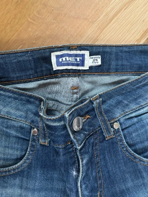 Blå skinny jeans från MET - Snygga blå skinny jeans från MET med slitningar och tvättade detaljer på låren och knäna. Klassisk femficksmodell med knappgylf och smala ben. Perfekta för en trendig och avslappnad look.