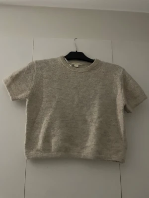 Stickad kortärmad tröja  - En  rätt så tjock mörk beige stickad tröja ifrån Gina Tricot. Den är aldrig använd så den är i väldigt bra skick och inga defekter. (Ser något ut som att de är missfärgning/fläckar är de ljuset. Skriv ifall ni vill ha bättre bilder) den är i storlek 146/152.