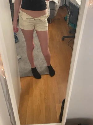 Vaniljvita shorts med fickor och knapp - Snygga vita shorts med medelhög midja och stora framfickor. Stängs med knapp och dragkedja framtill. Perfekta för sommaren och tillverkade i mjuk bomull som känns skön mot huden. Enkel och clean design som passar till det mesta.