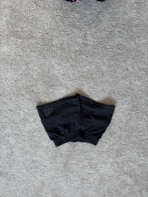 Svarta träningsshorts från Adidas - Säljer ett par svarta träningsshorts från Adidas med elastisk midja och diskret logga på sidan. Shortsen är tillverkade i ett mjukt och lätt material som passar perfekt för sport och aktivitet.