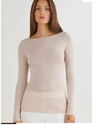 Beige långärmad topp i ullmix - Snygg beige långärmad topp med rund halsringning och tight passform. Tillverkad i mjuk ullmix som känns skön mot huden. Perfekt att styla med både jeans och kjol för en clean look.