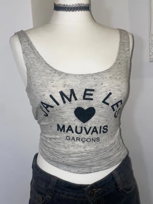 Grå linnetopp med tryck - Grå linnetopp med svart tryck 'J'aime les mauvais garçons'. Gjord på mjukt jersey material