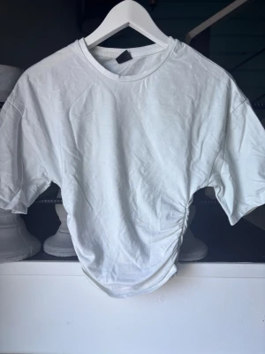 Vit t-shirt med snörning i sidan - Vit t-shirt Scrunch på båda sidorna och ger en tajt look vid midjan. Skriv för fler bilder. Tvättar såklart innan jag postar❣️