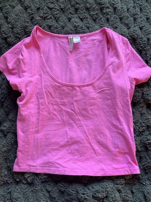 Rosa croppad topp  - Säljer en rosa croppad med rund, djup urringning och korta ärmar. Perfekt till jeans eller kjol för en trendig look. Tillverkad i mjuk bomull som känns skön mot huden.