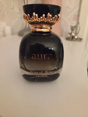 Aura Kiss of Rose parfym - Aura Kiss of Rose från La Fede är en söt och fräsch parfym från Khadlaj. Innehåll se bilder, uppskattar att ca 80 ml finns kvar. 